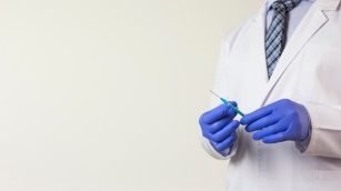 close-up-male-doctor-s-hand-wearing-blue-gloves-holding-syringe-hand-white-backdrop_23-2148050625